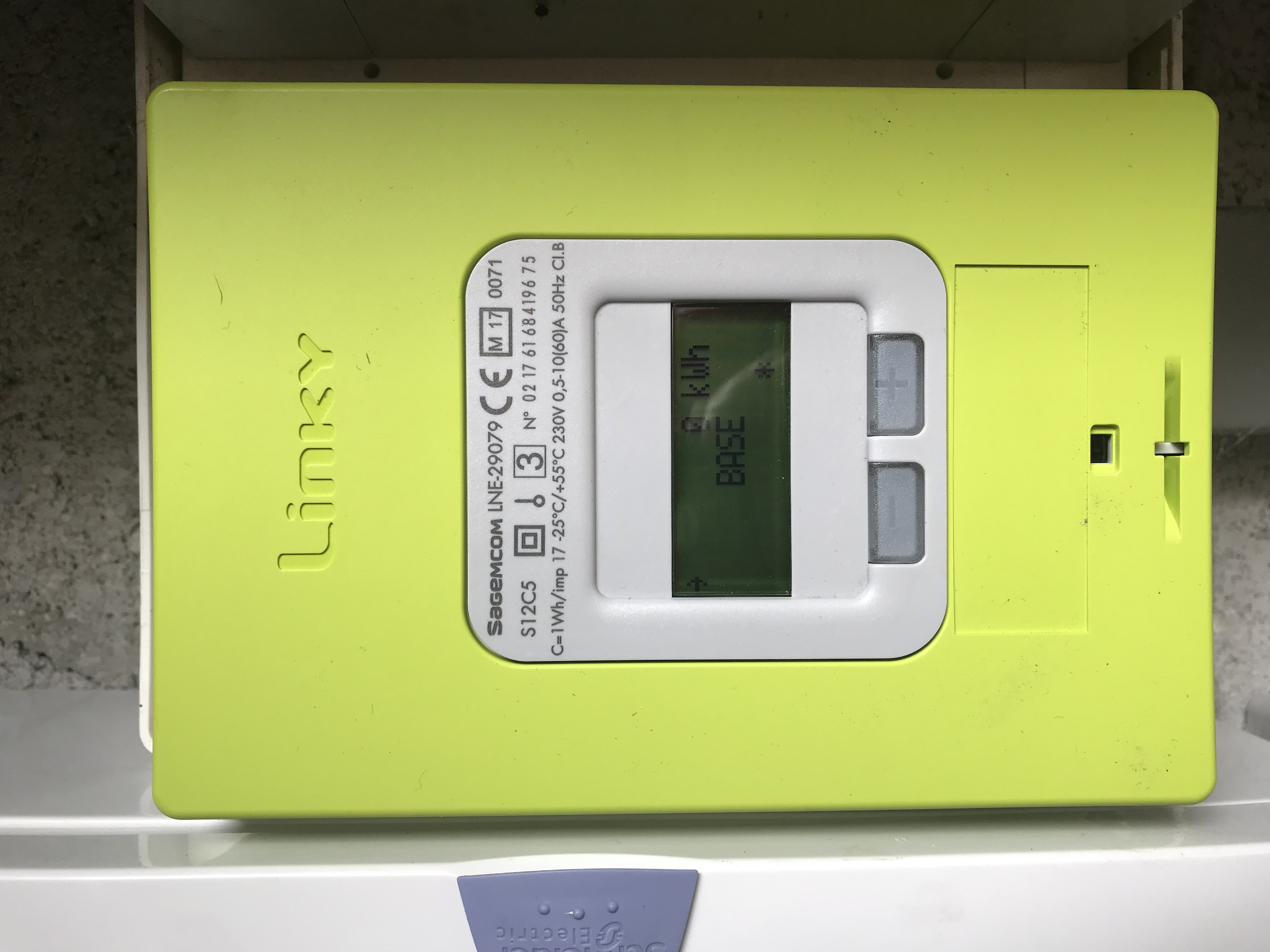 Compteur vert Linky fermé, écran LCD, deux boutons gris et inscriptions Sagemcom, S12C5 et 230 V visibles.